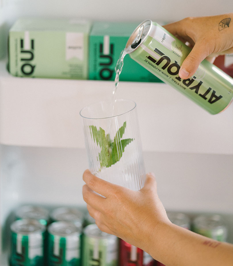 Hands pouring Atypique beverage from a can to a glass
